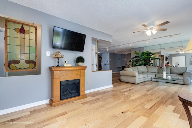 11207 Cottonwood Dr Unit 21C, Palos Hills, IL 60465 - living area with ceiling fan, wood finished floors, track lighting, a fireplace with raised hearth, and a textured ceiling