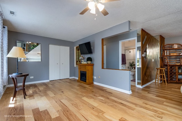 11207 Cottonwood Dr Unit 21C, Palos Hills, IL 60465 - unfurnished living room featuring wood finished floors, ceiling fan, a fireplace, and a textured ceiling