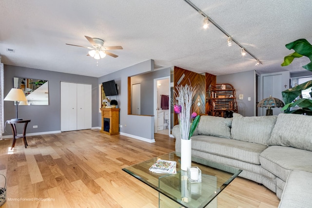 11207 Cottonwood Dr Unit 21C, Palos Hills, IL 60465 - living area with ceiling fan, light wood-style flooring, track lighting, a textured ceiling, and a fireplace