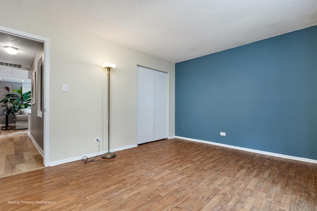 11207 Cottonwood Dr Unit 21C, Palos Hills, IL 60465 - unfurnished bedroom featuring wood finished floors, a textured ceiling, and a closet