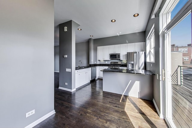 7501 Brown Ave Unit 3C, Forest Park, IL 60130 - kitchen featuring appliances with stainless steel finishes, dark countertops, white cabinetry, dark wood-style flooring, and a peninsula