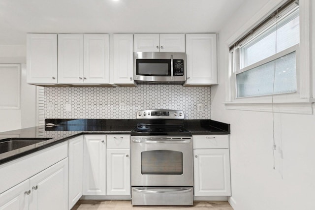 9445 W Kelvin Ln Unit 2992, Schiller Park, IL 60176 - kitchen featuring appliances with stainless steel finishes, white cabinets, decorative backsplash, and light wood finished floors