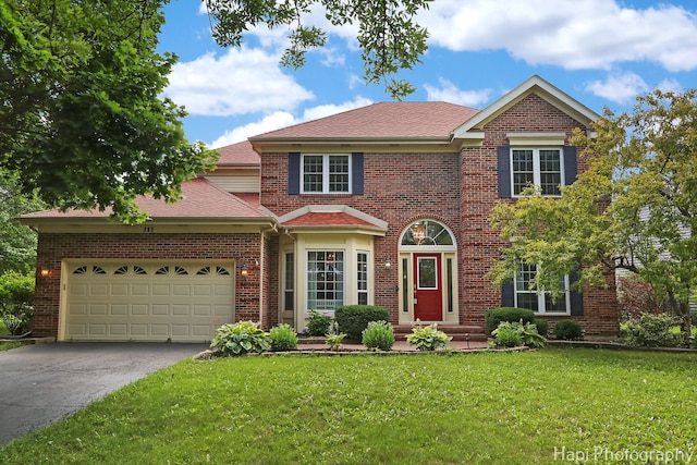 232 Bobolink Dr, Grayslake, IL 60030 - view of front of property with driveway, a garage, a front lawn, brick siding, and roof with shingles