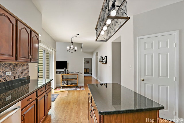 232 Bobolink Dr, Grayslake, IL 60030 - kitchen featuring a chandelier, light wood-type flooring, dark stone countertops, decorative backsplash, and a center island