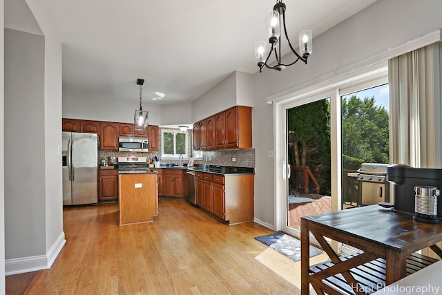 232 Bobolink Dr, Grayslake, IL 60030 - kitchen with appliances with stainless steel finishes, tasteful backsplash, dark countertops, a kitchen island, and light wood-type flooring
