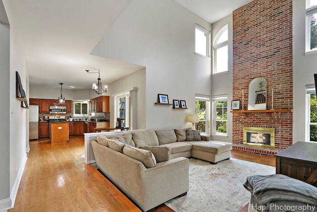 232 Bobolink Dr, Grayslake, IL 60030 - living room with a towering ceiling, light wood-type flooring, plenty of natural light, a fireplace, and a chandelier