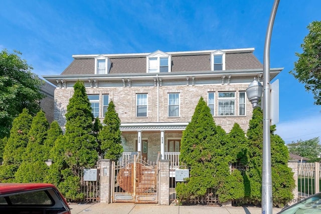 2318 S Central Park Ave Unit 101, Chicago, IL 60623 - second empire-style home with mansard roof, a gate, brick siding, and a porch
