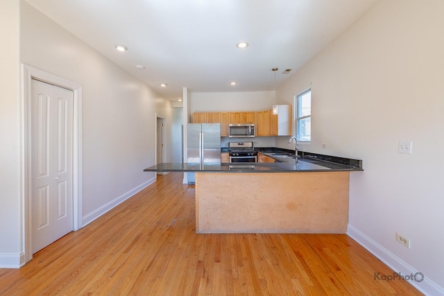 2318 S Central Park Ave Unit 101, Chicago, IL 60623 - kitchen with appliances with stainless steel finishes, a peninsula, light wood finished floors, hanging light fixtures, and dark stone countertops