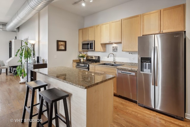 4011 N Francisco Ave Unit 310, Chicago, IL 60618 - kitchen featuring appliances with stainless steel finishes, light brown cabinetry, a kitchen island, light wood-style flooring, and a breakfast bar area