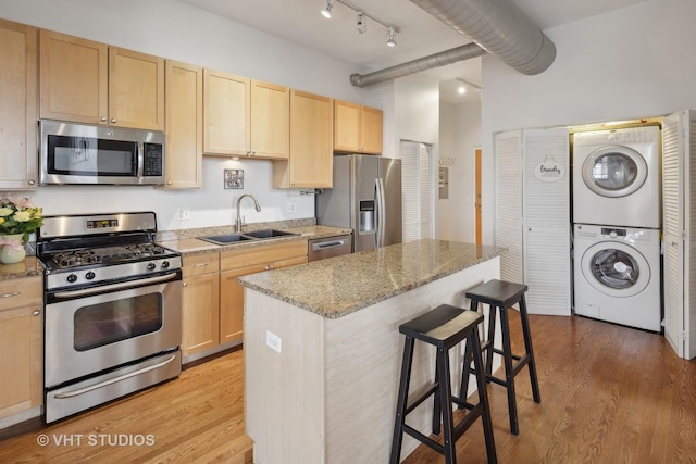 4011 N Francisco Ave Unit 310, Chicago, IL 60618 - kitchen with stainless steel appliances, light brown cabinets, stacked washer / drying machine, a kitchen bar, and light wood-style flooring