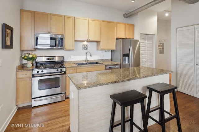 4011 N Francisco Ave Unit 310, Chicago, IL 60618 - kitchen with stainless steel appliances, light brown cabinetry, a breakfast bar area, wood finished floors, and light stone countertops