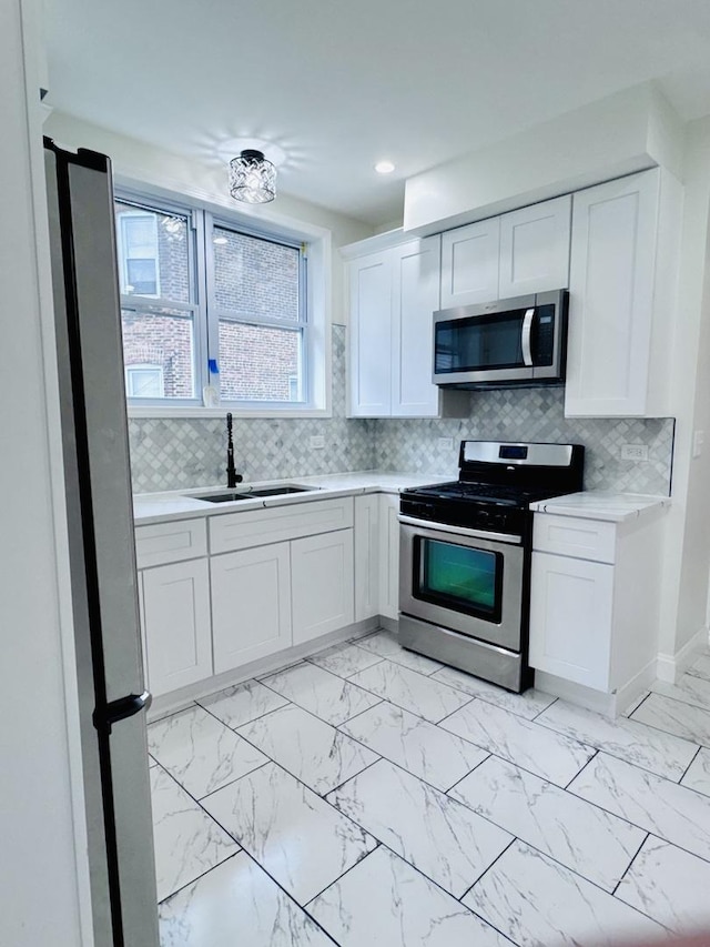 7253 S Marshfield Ave, Chicago, IL 60636 - kitchen featuring appliances with stainless steel finishes, light countertops, white cabinets, light marble finish flooring, and tasteful backsplash
