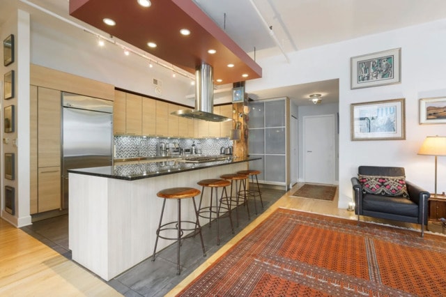 215 W Illinois St Unit 4C, Chicago, IL 60654 - kitchen with dark countertops, backsplash, wood finished floors, range hood, and a breakfast bar area