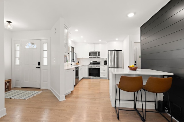 8378 Dunmore Dr, Tinley Park, IL 60487 - kitchen with appliances with stainless steel finishes, a kitchen bar, light countertops, light wood finished floors, and white cabinetry