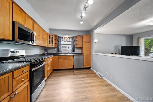 1885 Monday Dr, Elgin, IL 60123 - kitchen with stainless steel appliances, brown cabinetry, dark countertops, glass insert cabinets, and light wood-style floors