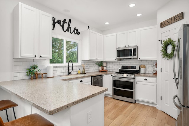 203 Stearn Dr, Genoa, IL 60135 - kitchen featuring stainless steel appliances, a peninsula, white cabinetry, tasteful backsplash, and recessed lighting