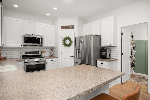 203 Stearn Dr, Genoa, IL 60135 - kitchen featuring appliances with stainless steel finishes, light wood-type flooring, white cabinets, and recessed lighting
