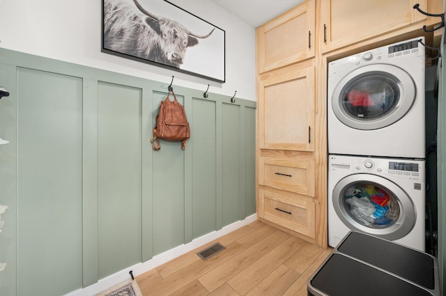 203 Stearn Dr, Genoa, IL 60135 - laundry area with cabinet space, stacked washer / drying machine, a decorative wall, light wood-style floors, and a wainscoted wall