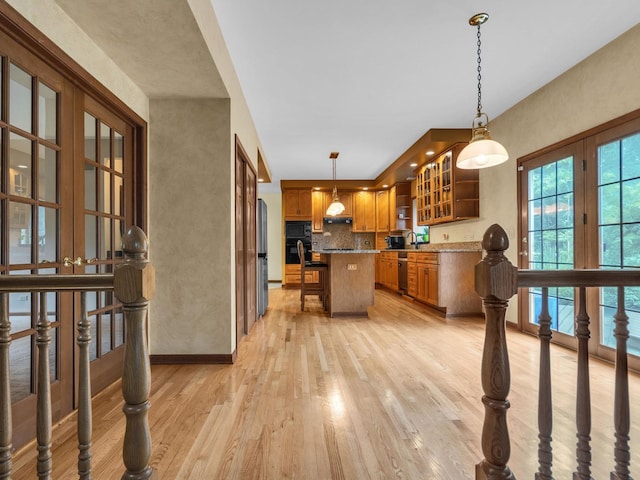 231 Deer Ln, Sleepy Hollow, IL 60118 - kitchen featuring brown cabinets, light wood-style floors, a center island, glass insert cabinets, and backsplash