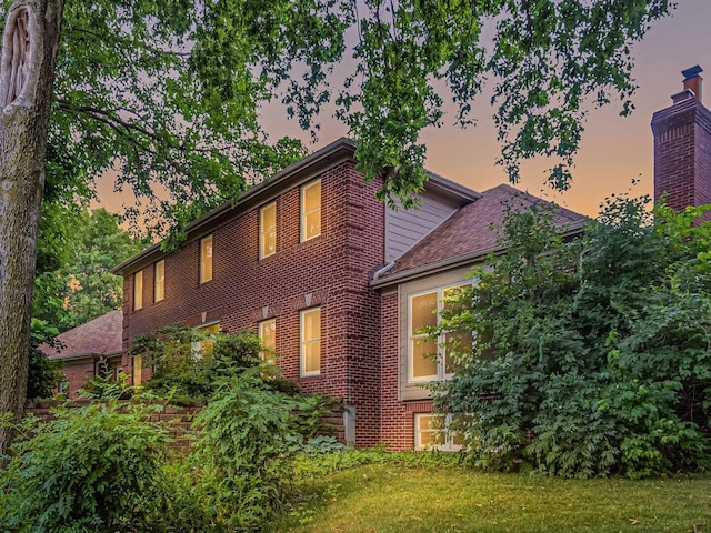 231 Deer Ln, Sleepy Hollow, IL 60118 - property exterior at dusk with brick siding, a lawn, and a chimney
