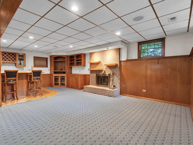 231 Deer Ln, Sleepy Hollow, IL 60118 - carpeted living area featuring wainscoting, bar area, a fireplace, wooden walls, and a drop ceiling