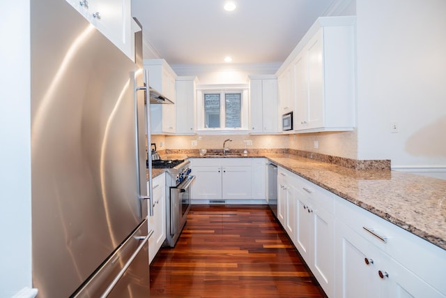 2418 N Southport Ave Unit 1, Chicago, IL 60614 - kitchen featuring appliances with stainless steel finishes, white cabinets, light stone counters, dark wood-style flooring, and ornamental molding