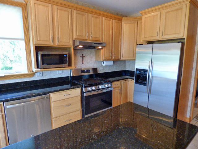 41W951 Hunters Hill Dr, Saint Charles, IL 60175 - kitchen featuring appliances with stainless steel finishes, under cabinet range hood, light brown cabinets, dark stone counters, and tasteful backsplash