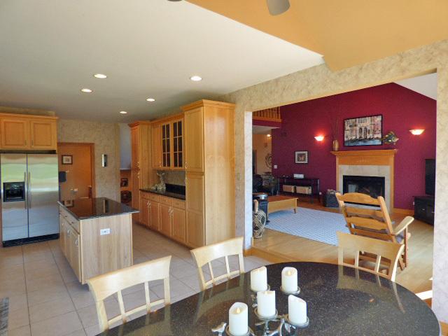 41W951 Hunters Hill Dr, Saint Charles, IL 60175 - kitchen featuring stainless steel fridge, a fireplace, a center island, glass insert cabinets, and dark countertops