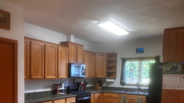1959 W Navajo Dr, Freeport, IL 61032 - kitchen with black range with gas cooktop, dark countertops, open shelves, freestanding refrigerator, and brown cabinets