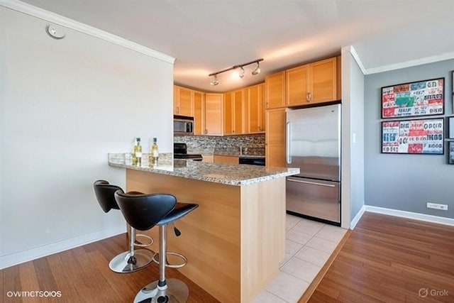 655 W Irving Park Rd Unit 5504, Chicago, IL 60613 - kitchen featuring stainless steel appliances, light wood finished floors, backsplash, a peninsula, and light stone counters