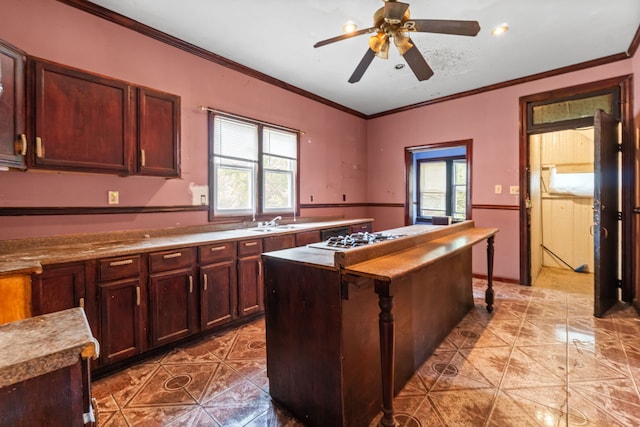 5212 S Honore St, Chicago, IL 60609 - kitchen featuring light tile patterned floors, a ceiling fan, gas stovetop, a kitchen island, and ornamental molding