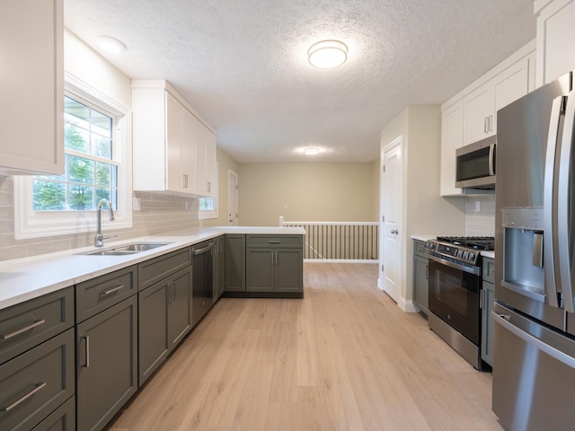 14746 Mercury Ln, Bloomington, IL 61705 - kitchen with stainless steel appliances, light wood-type flooring, white cabinets, a textured ceiling, and tasteful backsplash