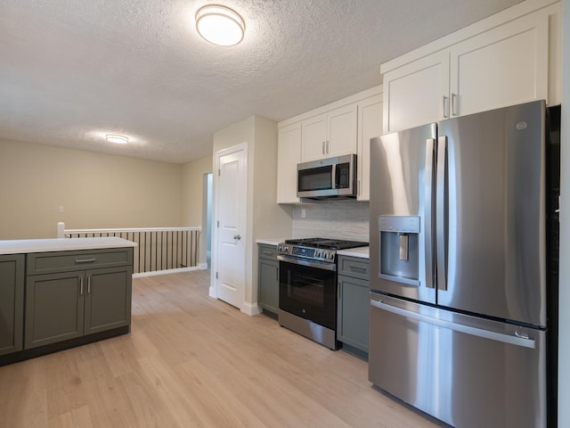 14746 Mercury Ln, Bloomington, IL 61705 - kitchen featuring appliances with stainless steel finishes, a textured ceiling, light wood-type flooring, light countertops, and backsplash