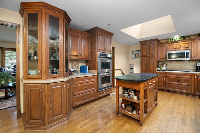 15630 Le Claire Ave, Oak Forest, IL 60452 - kitchen featuring appliances with stainless steel finishes, a skylight, light wood-style flooring, and decorative backsplash