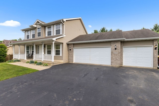 2225 National Sewing Ave, Belvidere, IL 61008 - view of front of property featuring a porch, asphalt driveway, a garage, and brick siding