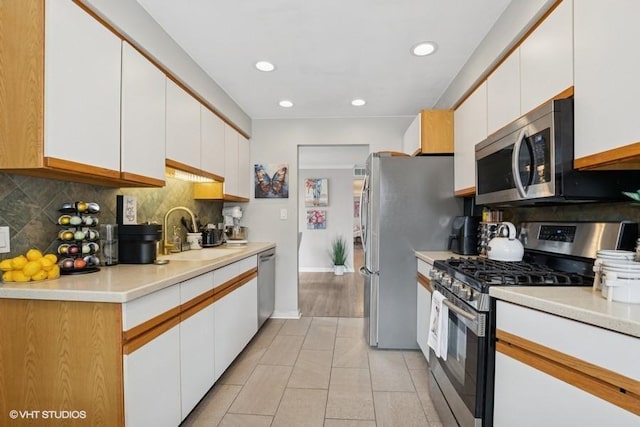 48 Parliament Dr W Unit 132, Palos Heights, IL 60463 - kitchen with appliances with stainless steel finishes, white cabinets, backsplash, light tile patterned flooring, and light countertops