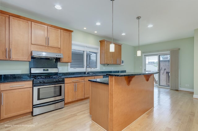 3129 N Oconto Ave, Chicago, IL 60707 - kitchen with stainless steel gas range, under cabinet range hood, light wood finished floors, a kitchen bar, and a kitchen island