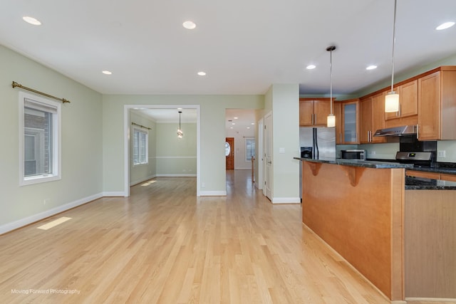 3129 N Oconto Ave, Chicago, IL 60707 - kitchen with appliances with stainless steel finishes, glass insert cabinets, a breakfast bar area, light wood-type flooring, and under cabinet range hood