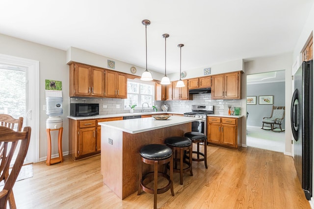102 Quinlan Ave, Dekalb, IL 60115 - kitchen with black appliances, under cabinet range hood, light wood finished floors, light countertops, and brown cabinets