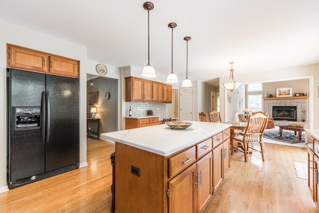 102 Quinlan Ave, Dekalb, IL 60115 - kitchen featuring black fridge with ice dispenser, light wood-type flooring, a kitchen island, and hanging light fixtures
