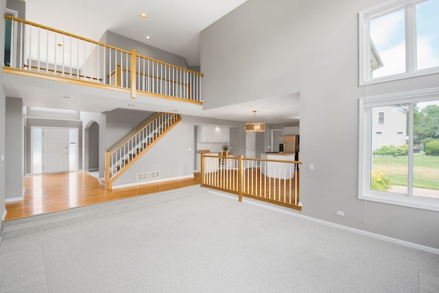 401 Kerry Ct, Prospect Heights, IL 60070 - unfurnished living room featuring carpet flooring, a high ceiling, stairway, arched walkways, and recessed lighting