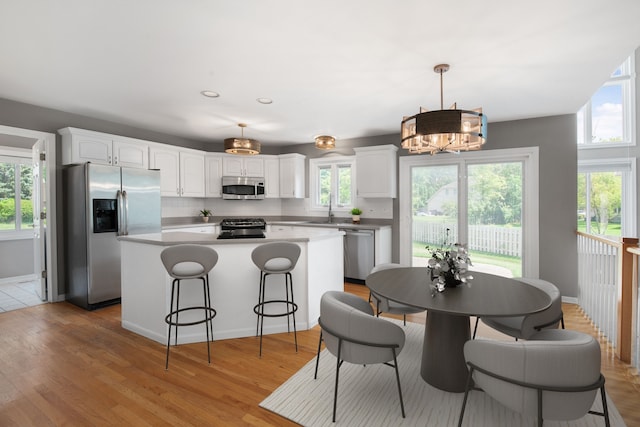 401 Kerry Ct, Prospect Heights, IL 60070 - kitchen with appliances with stainless steel finishes, a kitchen island, a chandelier, white cabinetry, and a breakfast bar