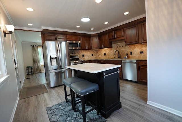 2304 Jay Ln, Rolling Meadows, IL 60008 - kitchen with appliances with stainless steel finishes, light wood-style floors, tasteful backsplash, a kitchen breakfast bar, and crown molding