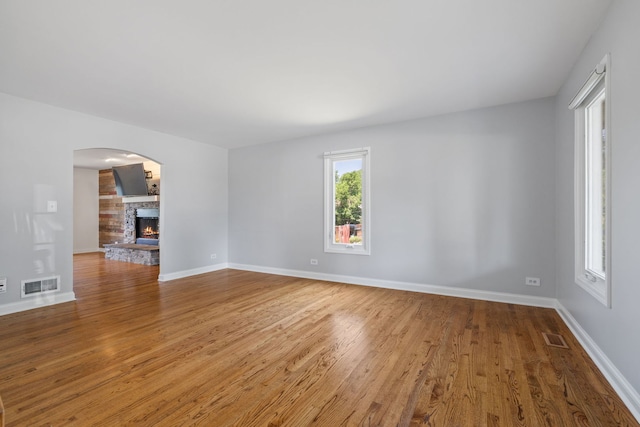 12351 W Warren Dr, Mokena, IL 60448 - spare room with wood finished floors, a stone fireplace, and arched walkways