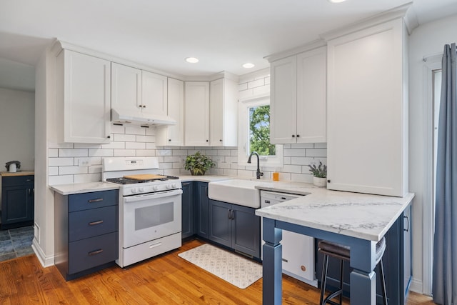 12351 W Warren Dr, Mokena, IL 60448 - kitchen with white gas range oven, under cabinet range hood, white cabinetry, blue cabinetry, and recessed lighting