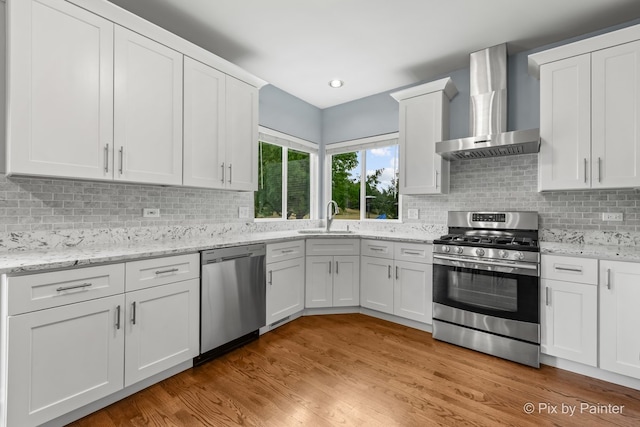 534 Ivory Ln, Bartlett, IL 60103 - kitchen with wall chimney exhaust hood, appliances with stainless steel finishes, white cabinets, light wood finished floors, and recessed lighting
