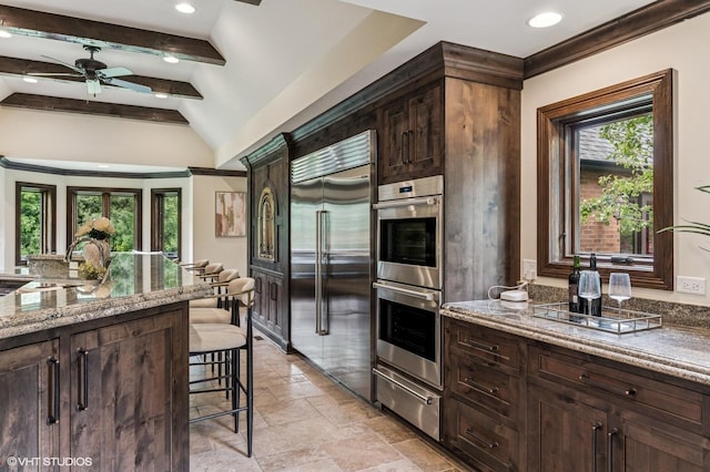 1899 Hilltop Ln, Bannockburn, IL 60015 - kitchen featuring stainless steel appliances, a warming drawer, a kitchen bar, stone tile flooring, and light stone counters