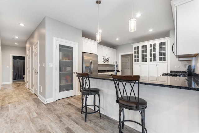 15710 S Cove Cir, Plainfield, IL 60544 - kitchen featuring stainless steel fridge with ice dispenser, a peninsula, range with gas stovetop, white cabinetry, and light wood-style floors