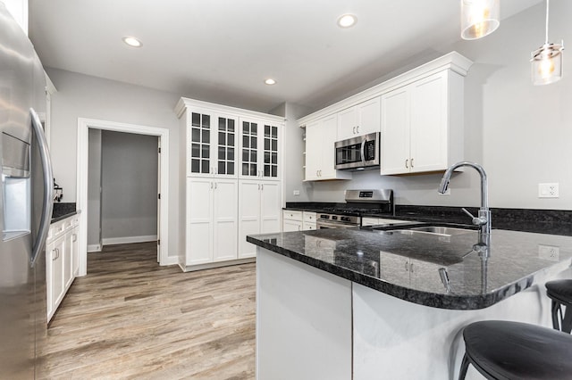 15710 S Cove Cir, Plainfield, IL 60544 - kitchen with stainless steel appliances, a peninsula, light wood-style floors, dark stone countertops, and white cabinets