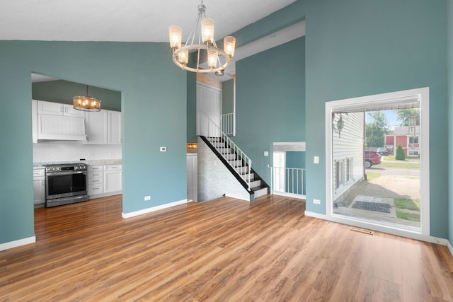 2S464 Cottonwood Ct, Warrenville, IL 60555 - unfurnished living room featuring high vaulted ceiling, a chandelier, stairway, and wood finished floors